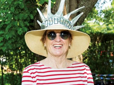 Woman in sunglasses and a statue of liberty hat.